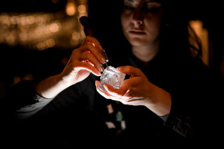 woman bartender with special device breaks pieces of ice.の写真素材