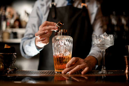 Close-up glass shaker with brown alcoholic drink and ice.の写真素材
