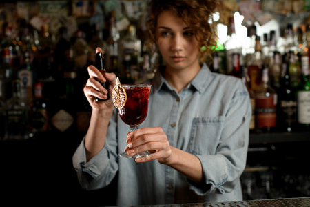 young woman bartender hold glass of drink in hand