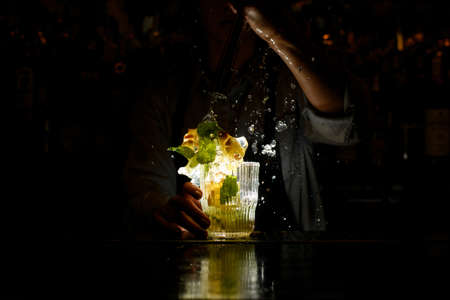 woman at dark bar energetically crushed cocktail with slices of citrus and ice.の写真素材