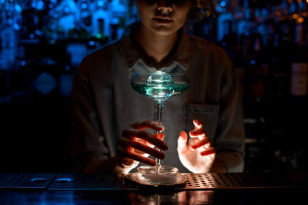 lady at bar holds very beautiful glass of blue cocktail.の写真素材
