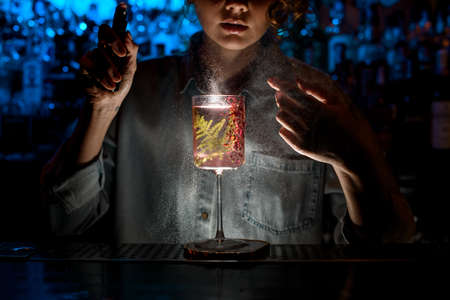 illuminated decorated glass with fresh pink cocktail stands at dark bar.の写真素材