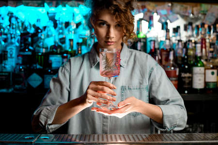 Pretty lady barman carefully holds glass in her hands.の写真素材