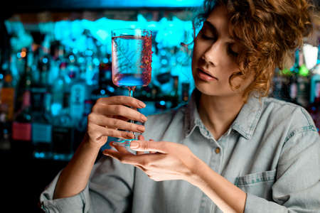 beautiful lady barman holds glass in her hands and looks at it.の写真素材