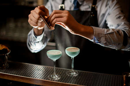 professional bartender decorates by grated nut ready-made cocktail in glasses.の写真素材