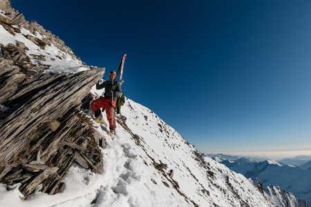 man with ski equipment leans to stone rock on mountain.