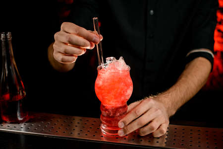 bartender decorates cocktail by glassy drinking tube.の写真素材