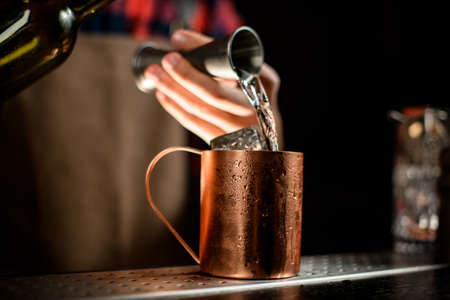 close-up metal cup into which bartender pouring liquidの写真素材