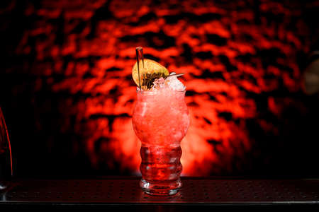 Close-up of glass with bright red cocktail decorated with slices of citrusの写真素材