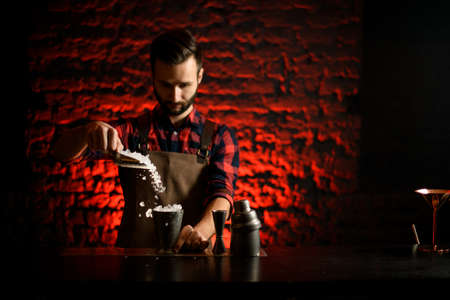 bartender hand pouring pieces of ice into metal cup.の写真素材