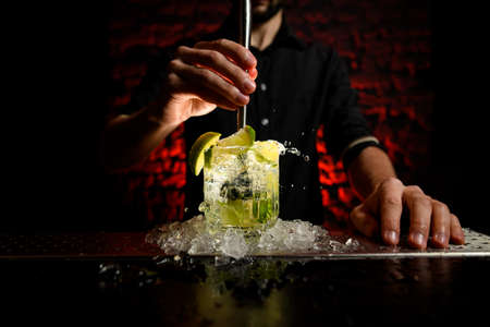 close-up barman actively mix cocktail using metal madlerの写真素材