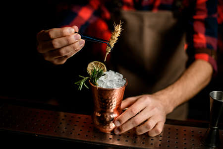 Close-up Barmans hand decorates with spikelet metal glass with ise using tweezersの写真素材
