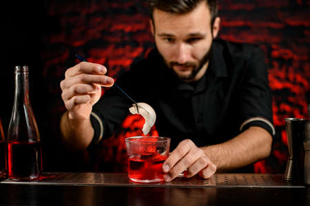 professional bartender decorates cocktail glass with two pieces of coconutの写真素材