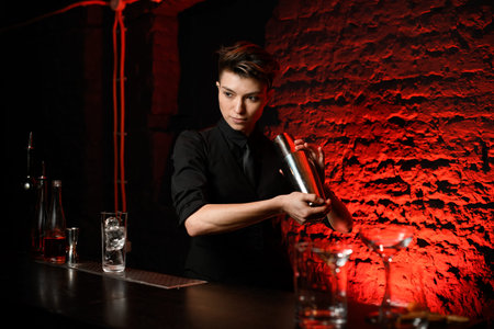 professional bartender holding steel shaker in her hands and mix it