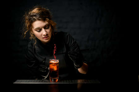 young bartender neatly decorates glass of cocktail with plants.の写真素材