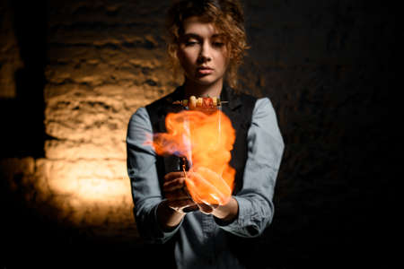 female bartender holding glass with cocktail sprinkles on it and masterfully make fire.の写真素材