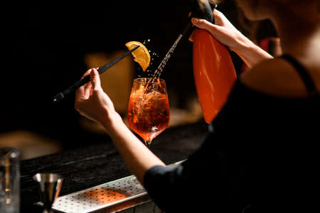 View on glass of cocktail which bartender girl decorates and pours carbonated drink.の写真素材