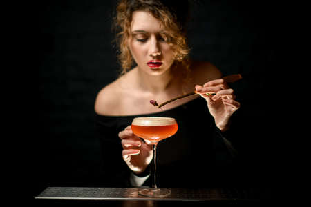 close-up. Attractive lady at bar decorates by flower glass with bright sour cocktailの写真素材