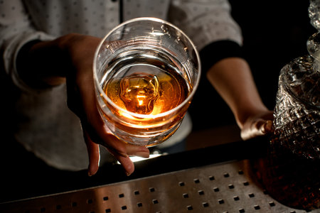 Close-up inside view of glass with cocktail that girl holds in her hand