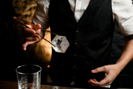 Close-up man holding large piece of ice using tweezers.