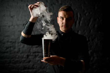 bartender holds smoky steel shaker in his hands.