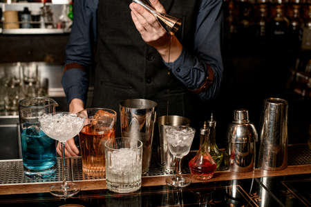 bartender carefully pours drink from jigger into shakerの写真素材