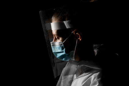view of young girl in medical mask and protective screen which looking down.