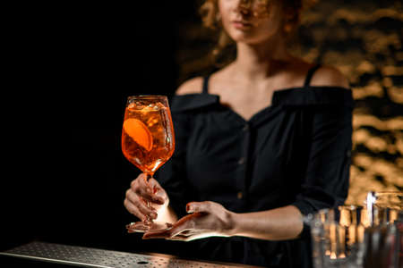 Pretty young woman at bar holds in her hand glass with cocktailの写真素材
