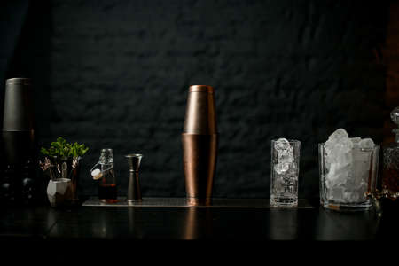 view of bar counter on which stands copper shaker and glasses with iceの写真素材