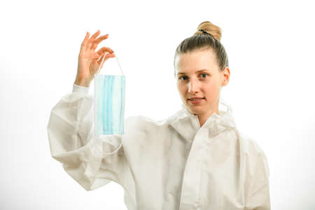 woman in white protective suit holds surgical mask in her handの写真素材