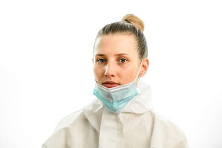 Portrait of young blonde woman with downcast medical mask on grey backgroundの写真素材