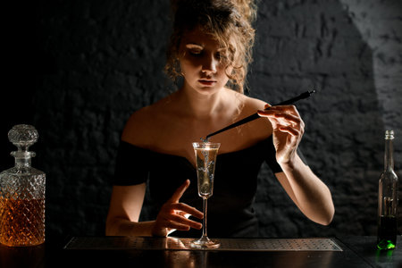 female bartender holds tweezers with plant over glassの写真素材