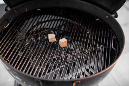Close-up of black grill grate with two small square wooden pallets for ignition. Barbecue...