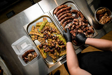 male cook spreads pieces of fried grill meat on metal tray.の写真素材