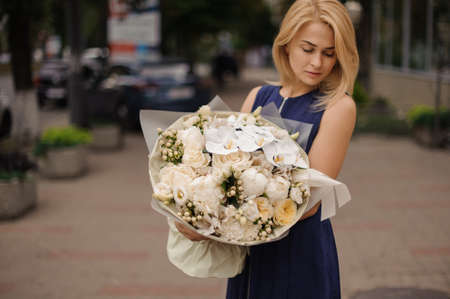 young blonde girl standing with large bouquet of white flowersの写真素材