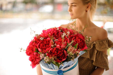young beautiful girl holds in hands big round box with red flowers.の写真素材