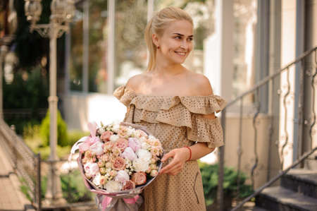 smiling woman holds beautiful delicate bouquet and looks awayの写真素材