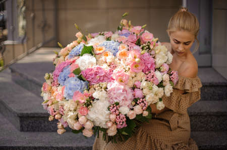 woman carefully holds huge bouquet of different flowersの写真素材
