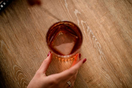 Top view on glass with drink and large square piece of iceの写真素材