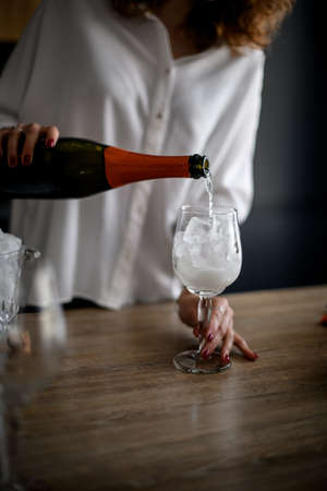 Close-up. Woman pours drink from bottle into glass with ice.の写真素材