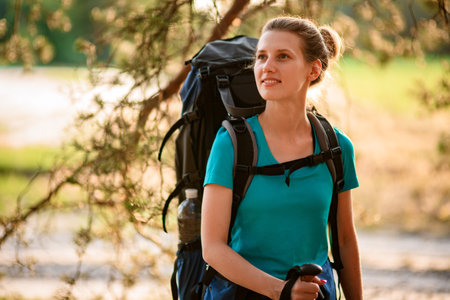 Close-up view of smiling woman with sport backpack which walking in forest