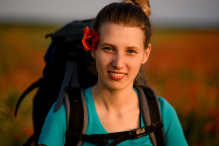 Portrait of young smiling woman with poppy flower on her head