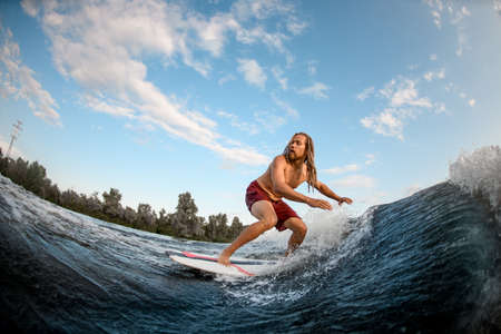 Active man wakesurfer balancing on wake board down the river wavesの写真素材