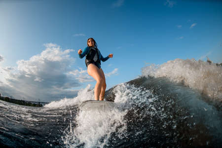 view of young woman wakesurfing down the river wavesの写真素材