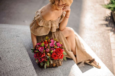 High angle view of woman with small basket filled with red fresh flowers.の写真素材