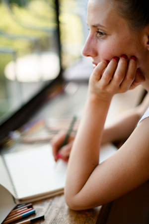 portrait of woman who props her head with her hand and looks out the window.