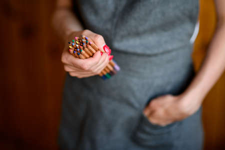 Closeup of womans hand with bunch of colored pencils in itの写真素材