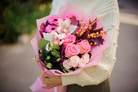Close-up of bouquet with roses, gerbera, orchids and berries in the hands of woman.の写真素材