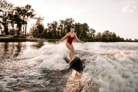 front view of woman who riding surfboard on wave.の写真素材