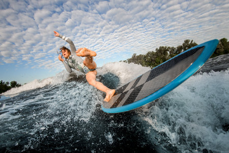 young woman falling from wake surfboard into the river water